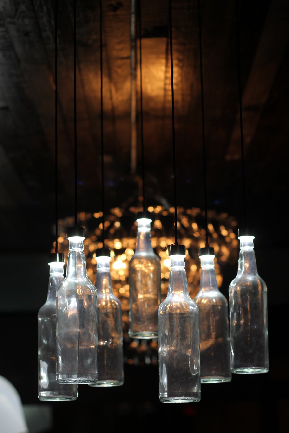 A chandelier made from clear glass bottles hanging above the room
