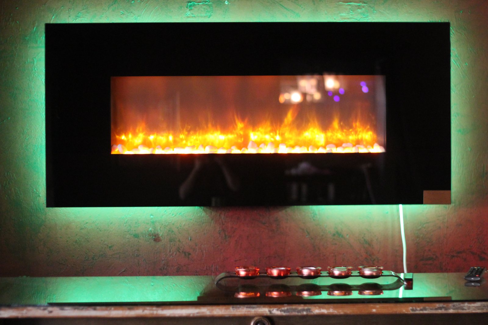 A long wall-mounted fireplace lit against a dark wall