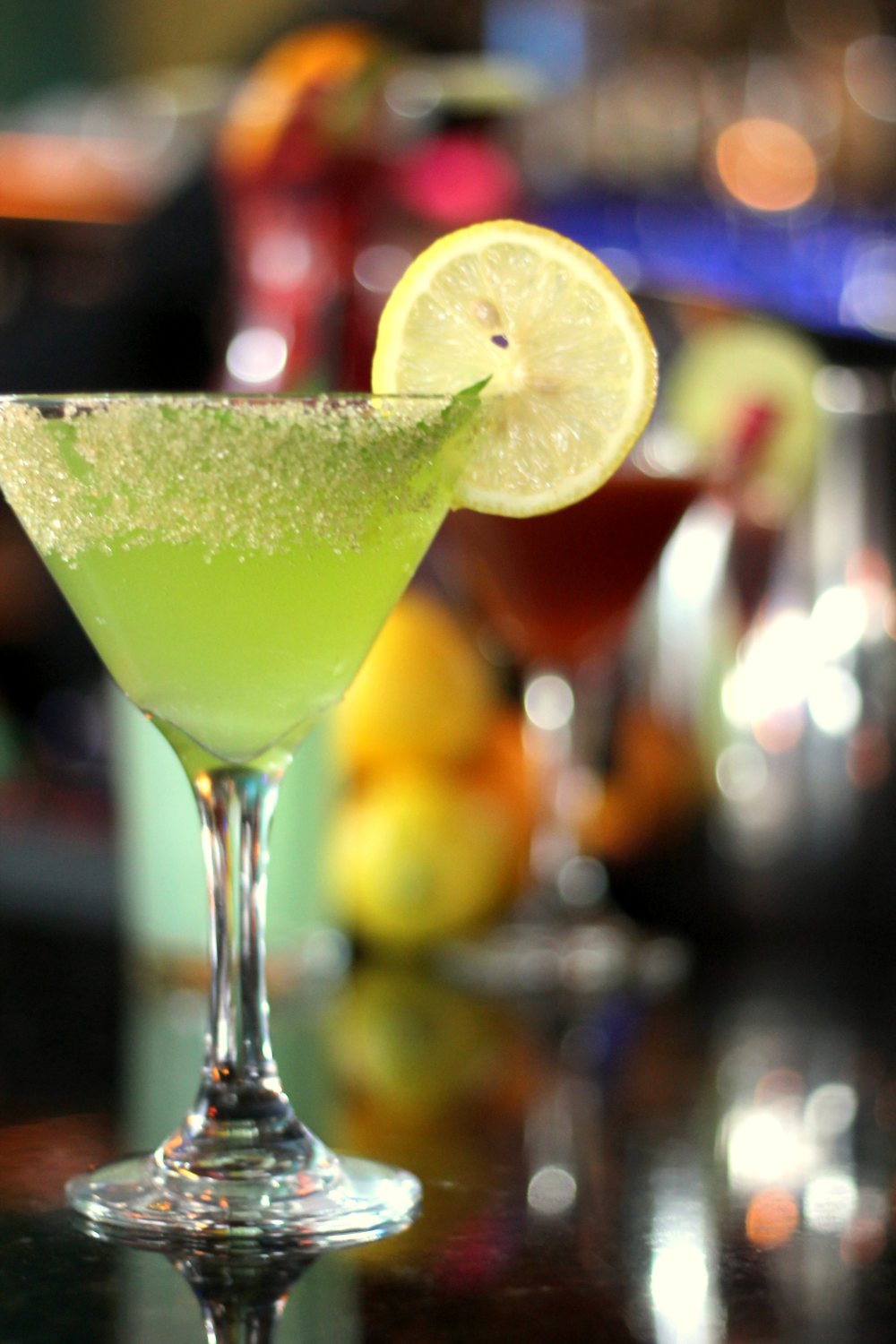 A pale green cocktail in a stemmed glass with a lime wheel
