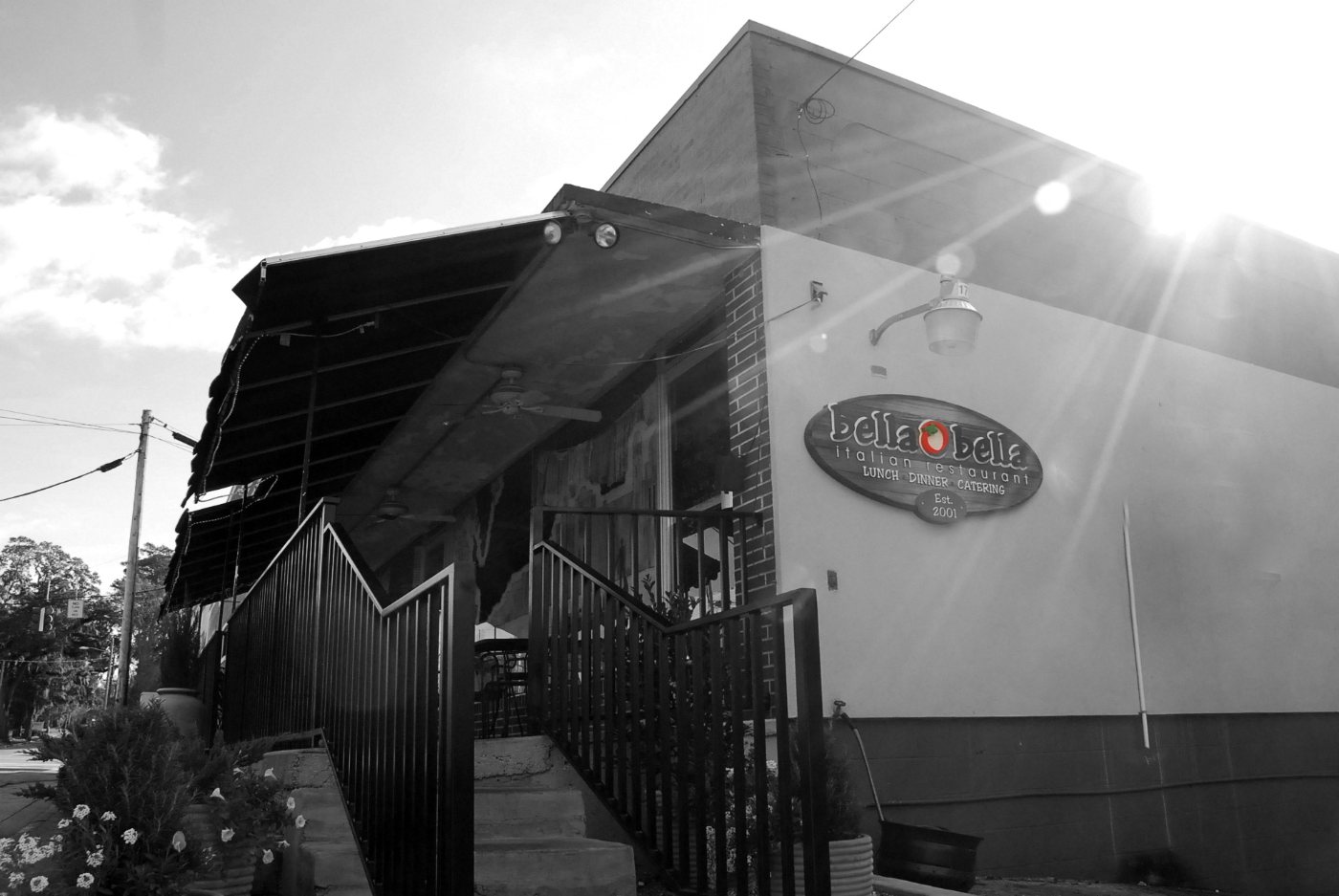 The restaurant from the street in black and white, its oval sign above the entrance