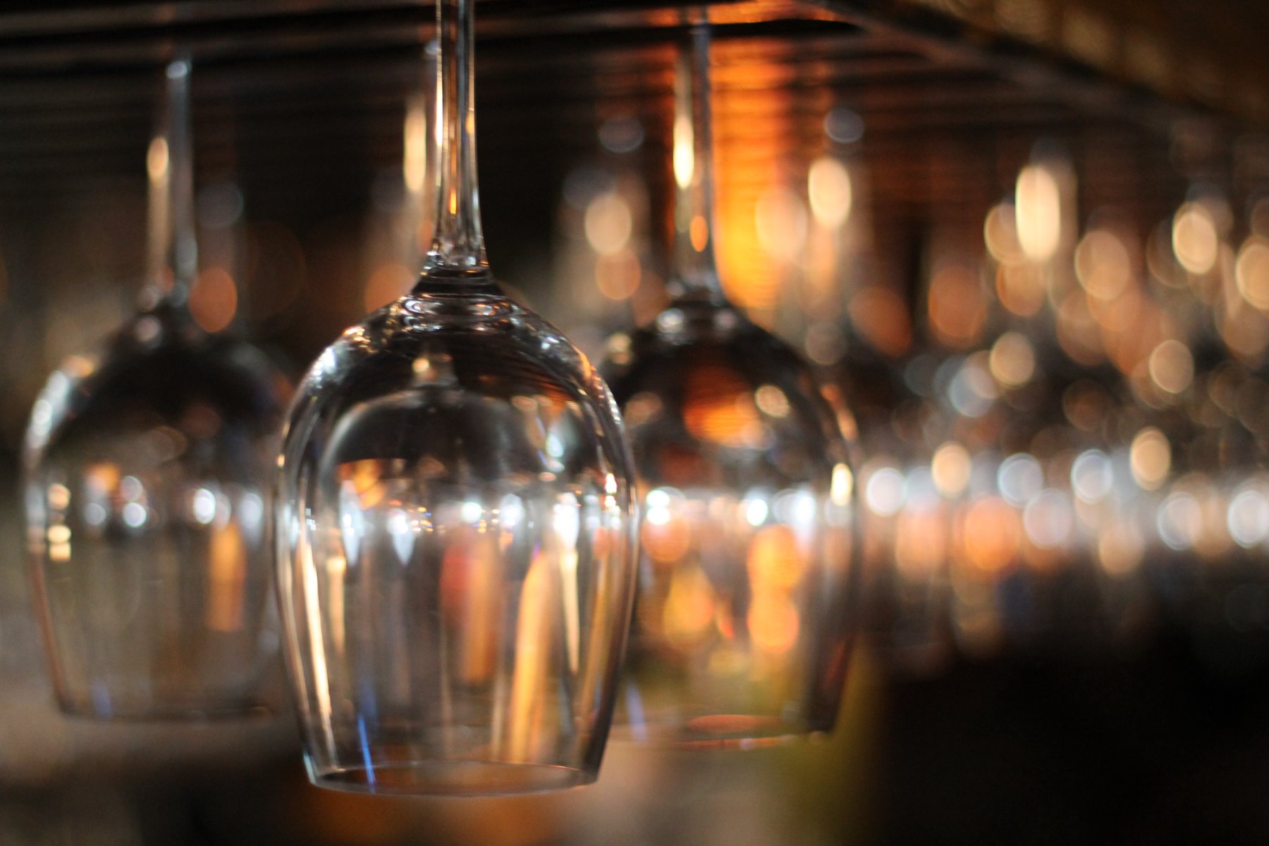 Wine glasses hanging upside down over the bar in warm light